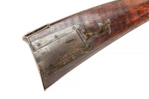 Close-up of a wooden buttstock of a rifle.