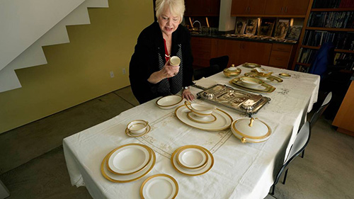 Al Capone's granddaughter, Diane Patricia Capone, examines family heirloom china that is laid out on a table.