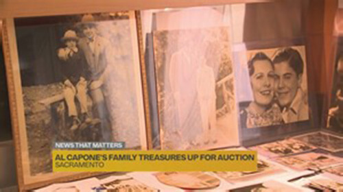 Screenshot from a news program. It is a close-up of a collection of some of Al Capone's family photos. The caption on the botom reads, 'Al Capone's Family Treasures Up for Auction'.