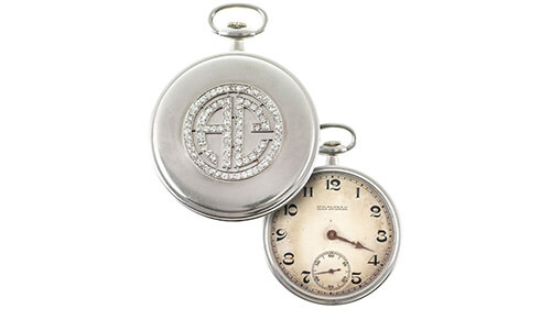 Close-up of two view of Al Capone's pocketwatch. On the left is the front of it with diamonds encrusted in Al Capone's initials. On the right is the watch face. There is some discoloration showing.