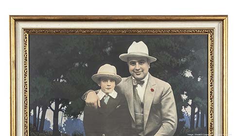 Close-up of a colorized version of a framed image of Al Capone with his young son. They are both wearing suits with ties and fedoras.